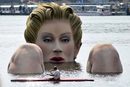 Мъж в кану плува около скулптура на морска сирена в езерото Алстер в Хамбург. Статуята, висока четири метра, ще бъде там до август 2012 г.