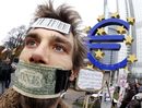 На 12 ноември протести имаше и пред централата на Европейската централна банка във Франкфурт, на които някои демонстранти (като този на снимката) бяха със залепени с доларови банкноти уста.<br /><br />Хиляди хора образуваха жива верига пред банката в знак на протест срещу мощта на банките по света.<br /><br />Полицията заяви, че над десет хиляди души са протестирали в два големи германски града срещу ролята на банките. Само във Франкфурт са били около 9000 демонстранти. В Берлин протестът е бил по-малоброен.<br /><br />