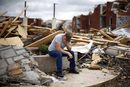 Мъж седи пред разрушения си блок, сринат след Торнадо в Мисури през май.