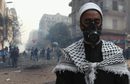 Египетски духовник демонстрант се моли, докато протестиращи бягат от сълзотворния газ, хвърлен от полицията по време на сблъсъци край площад "Тахрир" на 22 ноември.