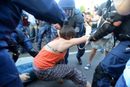 Полицаи се опитват да освободят платното, като издърпат блокиралите го хора
