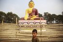 Дете играе пред гигантска статуя на  Буда в Лалитпур, югозападно от Катманду, където е родното място на Буда и е включено в списъка на ЮНЕСКО за световното културно наследство.