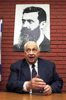 На фона на портрет на Теодор Херцел, бащата на ционизма, през февруари 2001 г., когато като бъдещ премиер преговаряше с победения си предшественик Ехуд Барак за съвместно правителство. 
При все че мнозина израелци не харесваха стила му на ръководител, на лично ниво Шарон бе приеман от всички - приятелски настроен, умеещ да ухажва и да изкушава.
