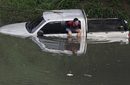 Мъж излиза през прозореца на колата си в наводнен от проливните дъждове район на Кали, Колумбия.