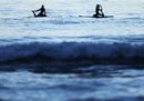 Момичета правят йога упражнения върху сърфове на плаж в Калифорния.