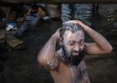 Мъж се къпе под спукан водопровод в бедняшки квартал в Мумбай, Индия.