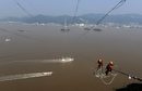 Работници инсталират компоненти за електрически кабели между пилони на остров в окръг Daishan, Китай.