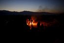 Хора се топлят на огън в импровизиран лагер за мигранти на гръцко-македонската граница в района на село Идомени, Гърция.