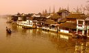 Миналият януари в Шанхай се спучи топъл (9-16С), с много слънчеви дни. След четири седмици на нови срещи със стари приятели, музеи, паркове, храмове, незабравими кулинарни приключения и пътувания до Хангдзоу, Судзоу, о-в Хайнан и старата столица Нанджин, напускаме 25-милионния мегаполис и се отправяме към 60-хилядния Дзуджаджао (Zhu Jia Jiao/Zhujiajiao, pinyin, "селището на семейство Дзу"). Закачливо, претенциозно, гордо или с идеи за маркетинг градът е наричан "Китайската Венеция". Има си и по-поетично име, напълно в духа на доста фантазно-бомбастичната китайска топонимия – Перлен Извор. (При интерес, пътеписът може да има следваща част- класическата кит. градина Kezhi в Дзуджаджао)<br /><br />Градът има 1,800-годишна история, с развито тъкачество и риболов в миналото. Прорязан е от многобройни канали по реката Чинг (Qingpu, pinyin), а отделните му части са свързани с 36 каменни и множество дървени мостове.