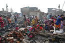 Жена стои сред развалините на дома си след пожар в бедняшки квартал в Делхи, Индия.