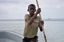 Момче помага на капитана да вкара лодката в открито море, за да поемем към поредното приключение на острова – гмуркане с делфини.