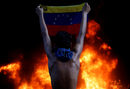 Протестиращ държи венецуелското знаме пред входа на Върховния съд в Каракас, 12 юни. "Сблъсъците бяха по-интензивни от обичайното. Протестиращите разграбиха клон на банка в същата сграда, където после пламна пожар. Няколко бяха ранени и задържани," разказва Карлос Гарсия Роулинс.