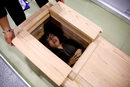 Посетител на изложение за погребални и церемониални услуги в Токио изпробва ковчег.
