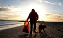 Доброволката Пам Майкъл събира пластмасови и други отпадъци докато се разхожда с кучето си Джордж по плажа на Ню Брайтън близо до Ливърпул, Великобритания.