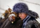 Млад ловец си почива до своя опитомен орел на годишния конкурс за ловци в Алмати, Казахстан.