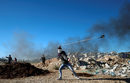 Палестинец хвърля камъни по израелската полиция по време на сблъсъци близо до Рамала, Западния бряг.