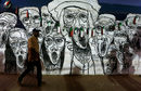 Суданец - участник в антиправителствен протест, минава покрай стени с изрисувани графити в столицата Хартум.