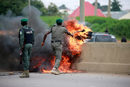 Полицаи премахват горящи гуми, запалени от протестиращи срещу управлението в Абужа, Нигерия.