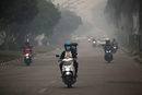 Мотористи минават през пушек от горски пожар в провинция Калимантан, Индонезия.