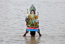 Поклонник носи статуя на индуисткият бог на архитектурата Вишвакарма, за да го потопи във водите на река Ганг в Колката, Индия.