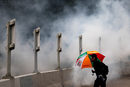 Протестиращ срещу правителството се пази от сълзотворен газ по време на демонстрация в квартал в Хонконг, Китай.