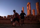 Момчета играят футбол пред Храмът на Херкулес в цитаделата на Аман, Йордания.