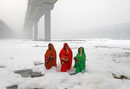Индуистки жени почитат бога на слънцето в замърсените води на река Ямуна по време на индуистки религиозен фестивал в Ню Делхи, Индия.