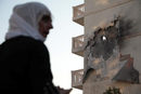 Жена стои пред жилищна сграда, която е била повредена от ракета, изстреляна от Сирия в Нусайбин, Турция.