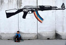 Ваксаджия чака клиенти под графит на стена в Кабул, Афганистан.