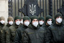 Членове на Националната гвардия на Украйна, носещи медицински маски за лице, стоят на пост пред сградата на парламента в Киев.