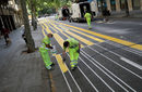 Работници боядисват част от улицата, за да разширят тротоара за пешеходци в Барселона, Испания.