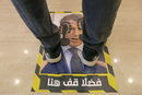 Мъж стои върху стикер за социално дистанциране, със снимка на френския президент Еманюел Макрон в магазин в Триполи, Либия.