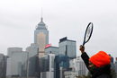 Треньор по тенис вдига ракетата си в знак на протест срещу ограниченията върху спортните съоръжения и спорта на открито в Хонконг заради пандемията от коронавирус (COVID-19), Китай.