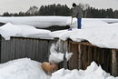 Мъж почиства дървена постройка в двора си от падналия сняг в сиберското село Бобровка, Русия.