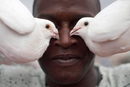 Колекционер на гълъби позира за снимка с два от тях на покрива на жилищна сграда в Хавана, Куба.