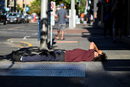 Мъж лежи на тротоар в горещ летен ден в Портланд, Орегон, САЩ.