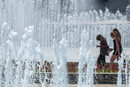Момичета се разхождат близо до фонтана на НДК в горещ летен ден