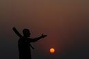 Силует на мъж с бухалка за крикет на фона на залязващото слънце в Карачи, Пакистан.