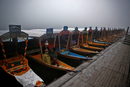Туристи седят в една от лодките на брега на езерото Дал през студената и мъглива сутрин в Шринагар.