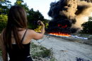Жена снима с телефона си изгарянето на 135 пакета кокаин, конфискуван от властите в Ел Салвадор.