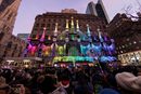 Хора наблюдават светлинна прожекция на Saks Fifth Avenue в Ню Йорк, Ню Йорк.