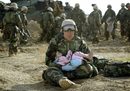 Американски военен държи на ръце малко дете, осиротяло, след като семейството му е било убито погрешка в Централен Ирак (29 март, 2003 г.). Седмица по-рано армията на САЩ сложи началото на война, целяща да свали от поста му диктатора Саддам Хюсеин.