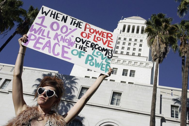 Девойка държи транспарант с надпис: "Когато силата на любовта надделее над любовта към властта, всичките 100% ще имаме мир" пред кметството