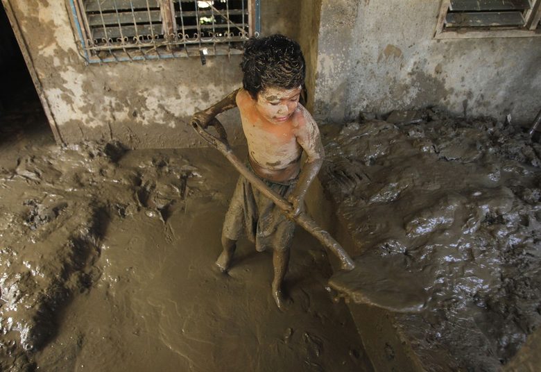 Дете разчиства дома си от калта след голямото наводнение във Филипините през декември, предизвикано от тайфуна Уаши, който отне живота на близо 1000 души.