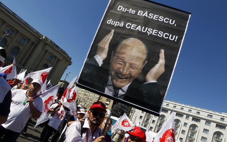 Румънски демонстранти държат плакат, оприличаващ президента Траян Бъсеску на комунистическия диктатор Николае Чаушеску