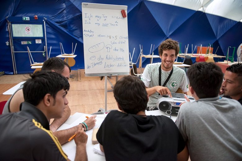 Германският стажант Адам преподава немски език на имигрантите в центъра за спешно настаняване в Берлин.