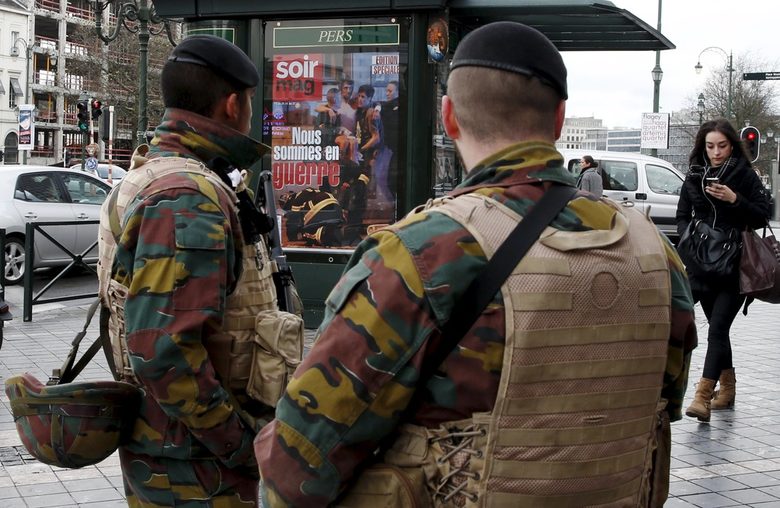 Войници в центъра на Брюксел до павилион с реклама на местно списание с водещо заглавие "Във война сме".