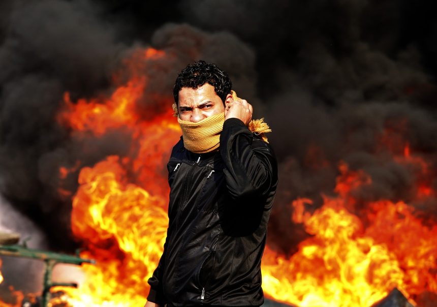 Демонстрант стои пред запалена барикада на площад "Тахрир" в Кайро на 28 януари. Полицаи и демонстранти водиха ожесточени битки по улиците на египетската столица в хода на революцията, която сложи край на трийсетгодишното управление на президента Хосни Мубарак.