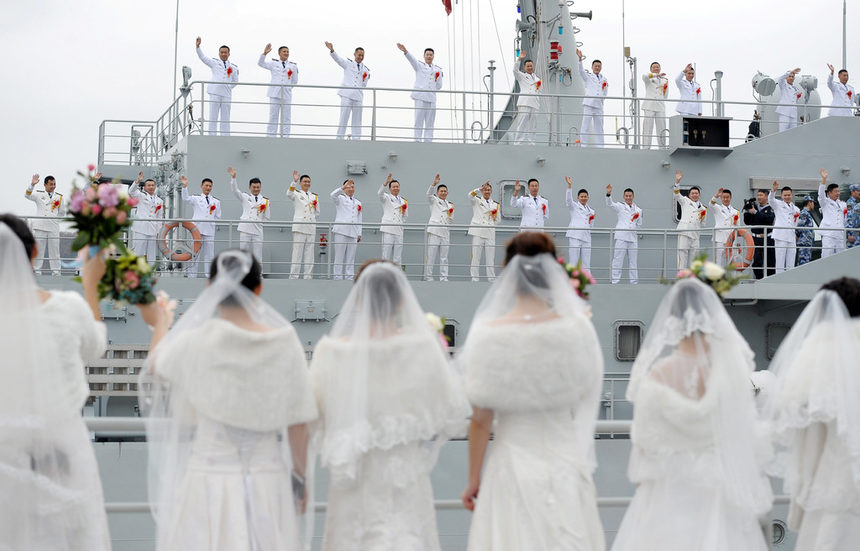 Военнослужещи от военноморските сили на Народната освободителна армия махат на своите съпруги по време на масовата сватба във военна база в Китай.