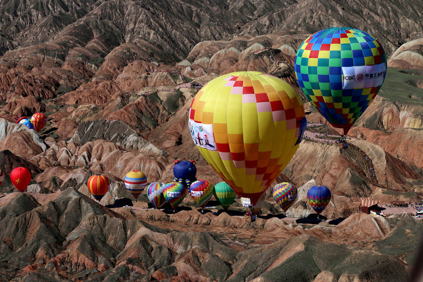 Балони с горещ въздух летят над живописна местност по време на фестивал в провинция Гансу, Китай.
